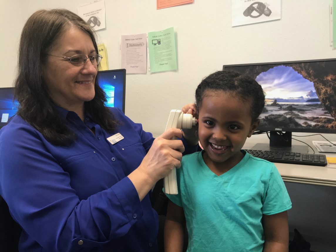 woman checking a little girl’s ear