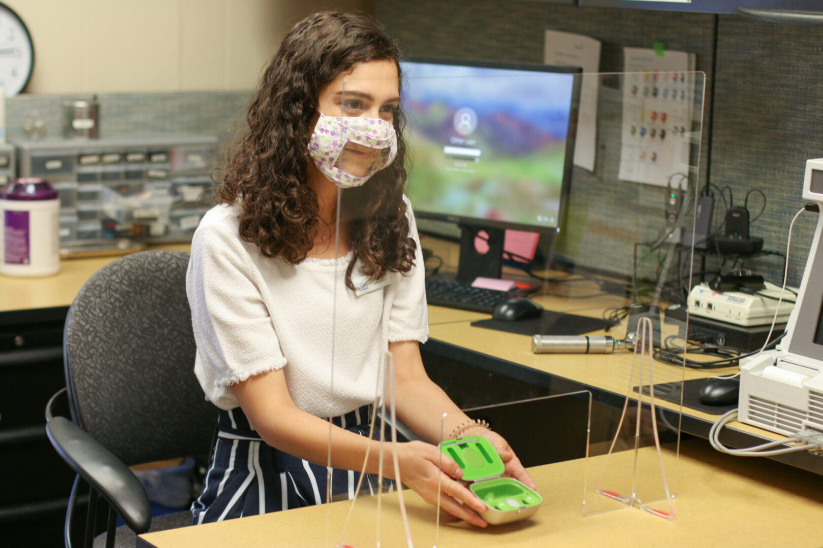 A girl wearing a face mask and holding a small, green case