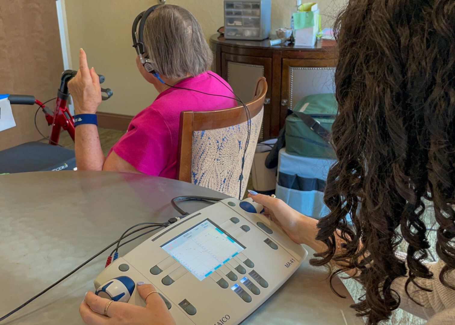 Dr. Emory Bratton tests a resident's hearing with a portable audiometer.