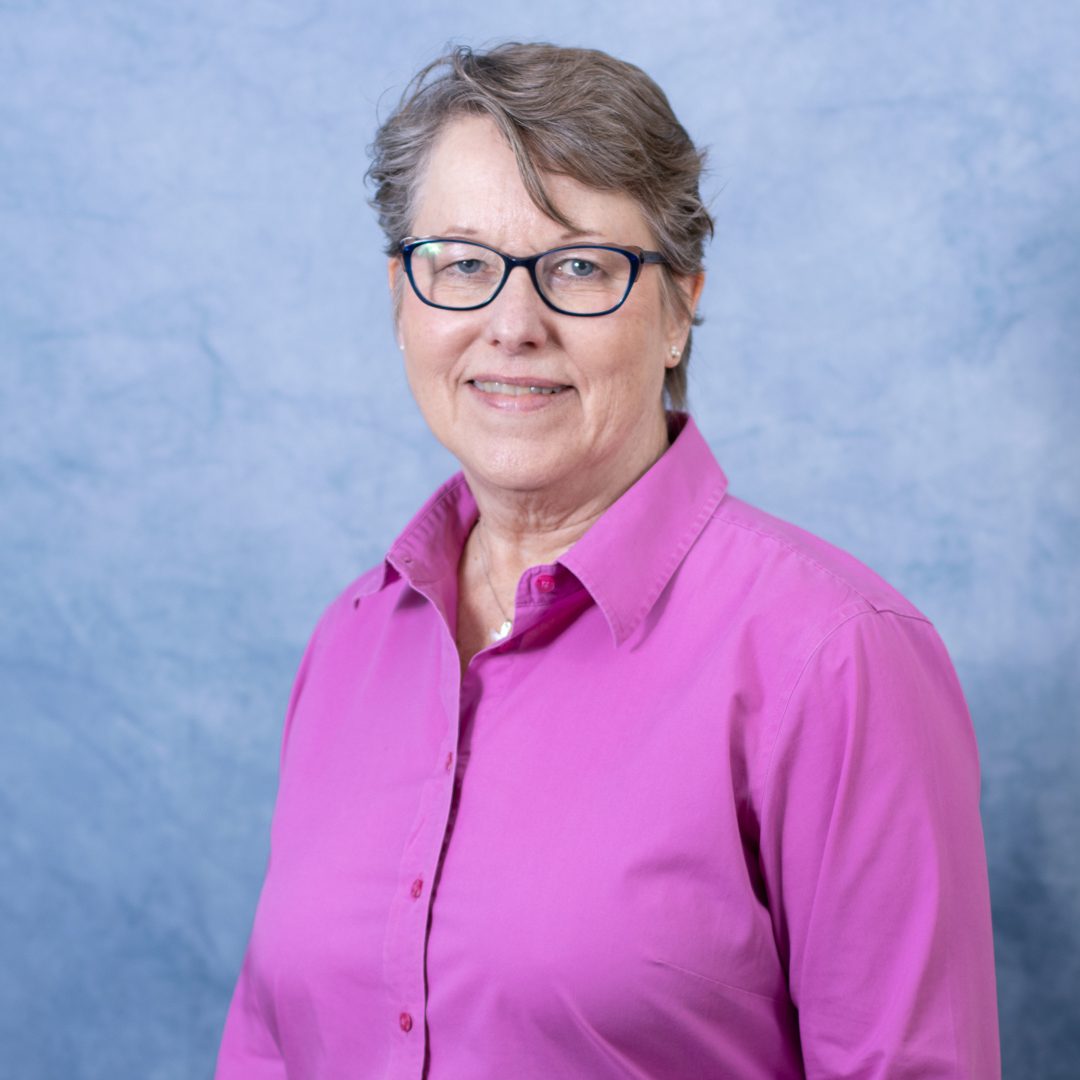 Woman in pink shirt with glasses.