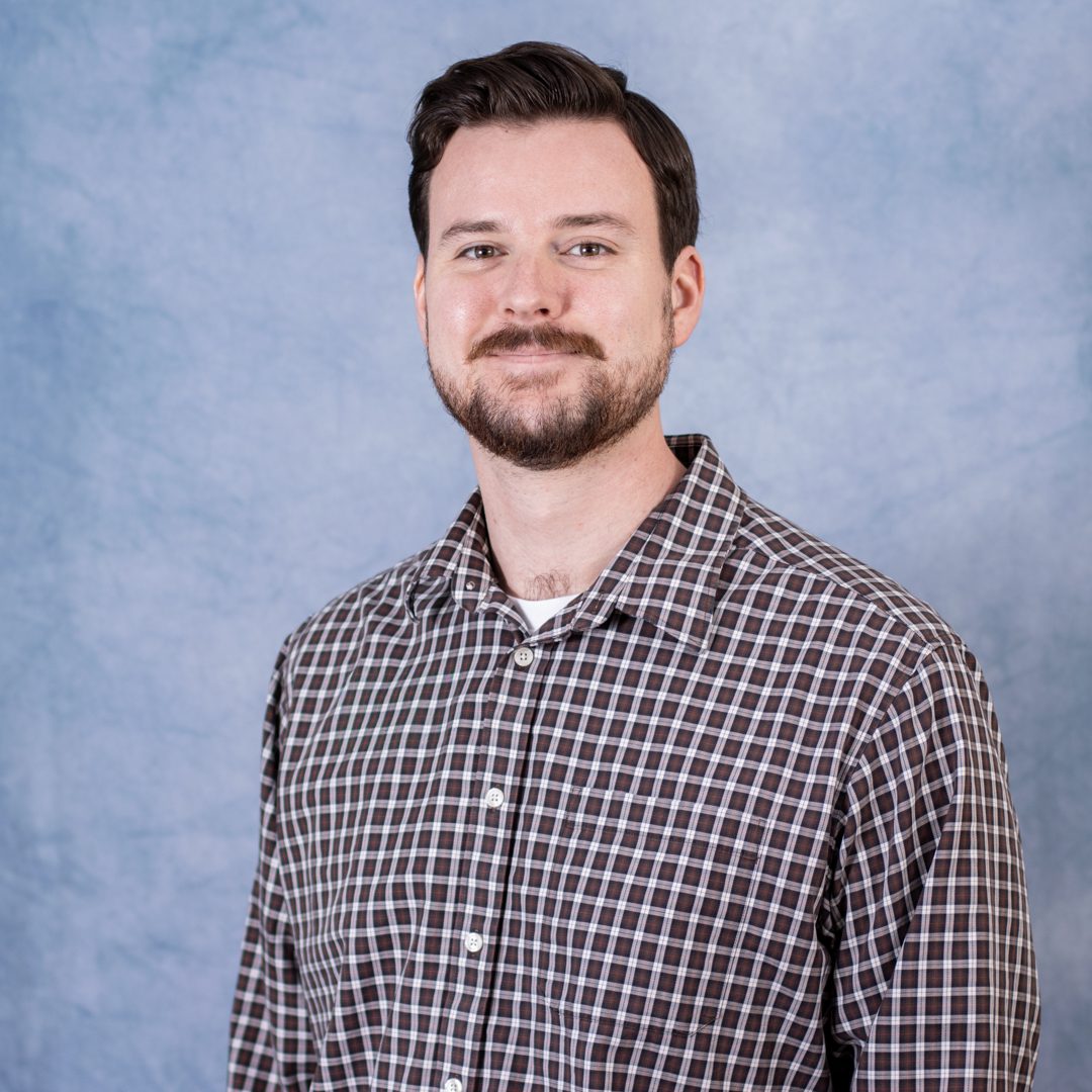Man in plaid shirt against blue background.