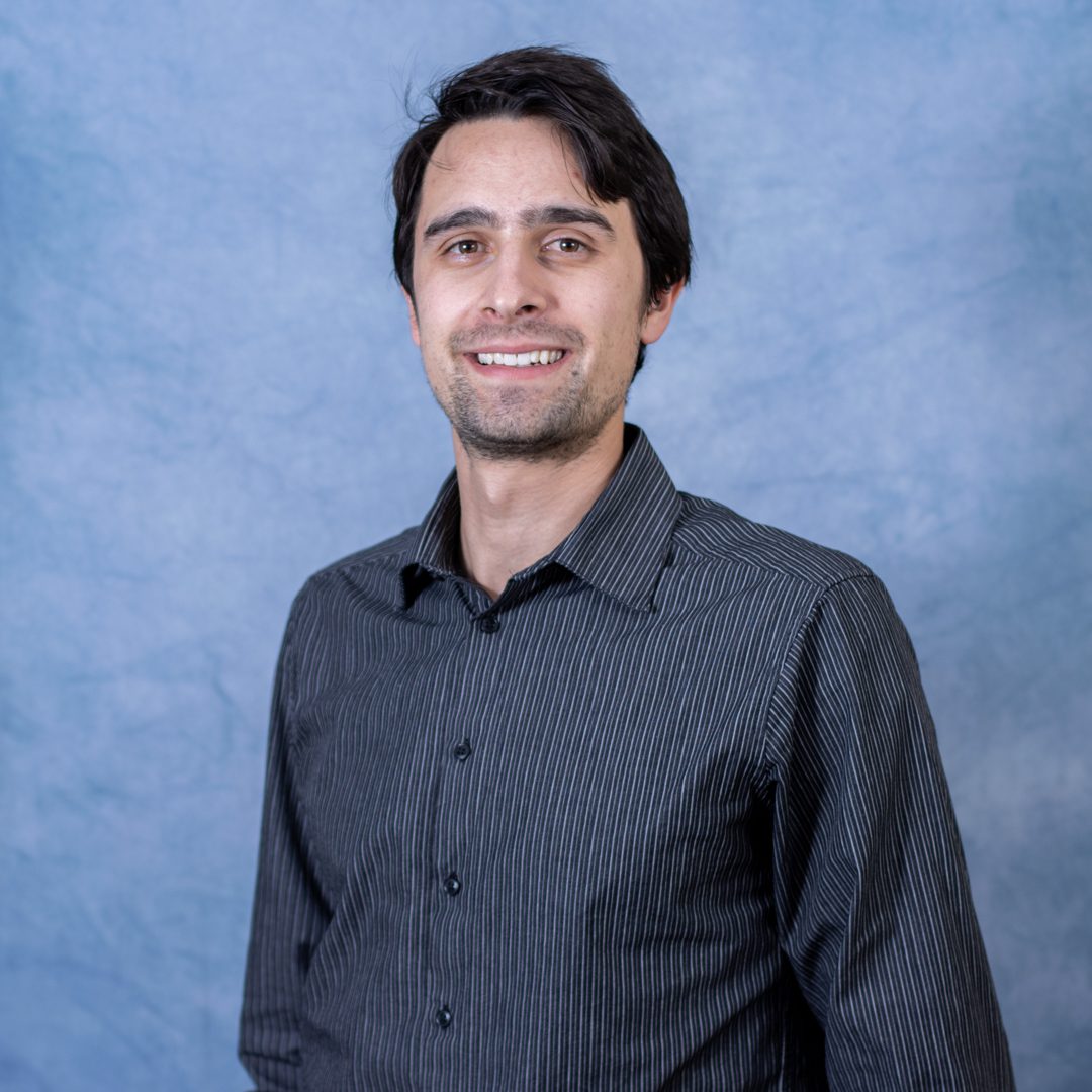 Man smiling in front of blue background.