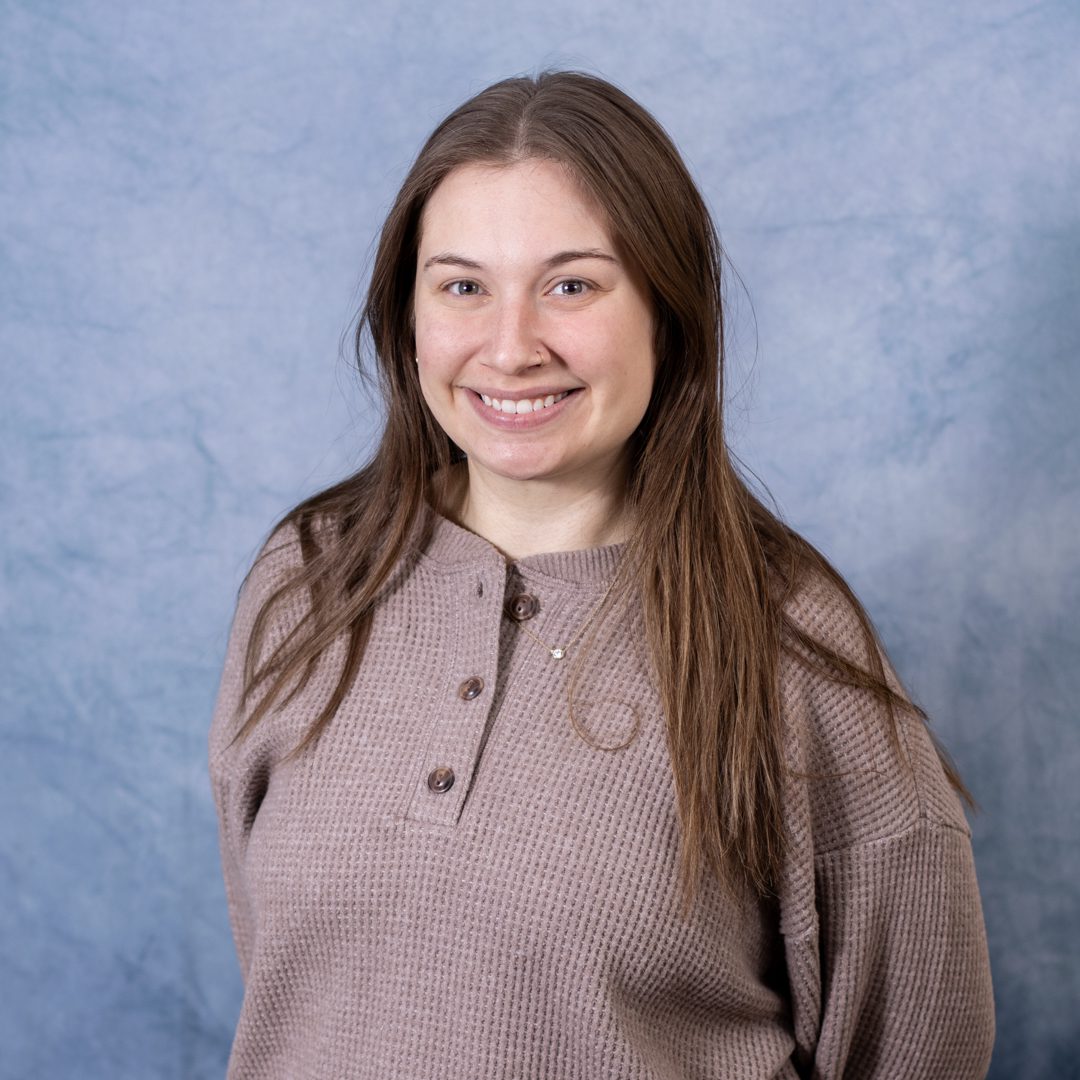 Smiling woman in a brown sweater.