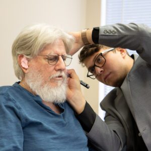 Man with beard getting ear examined.