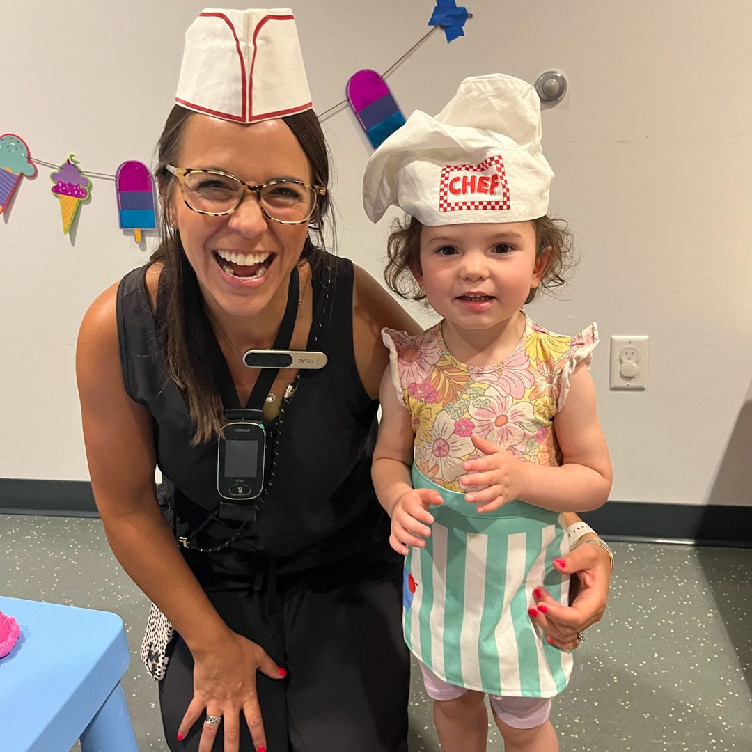 Woman and child wearing chef hats, smiling.