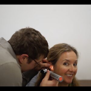 Doctor examining woman's ear with otoscope.
