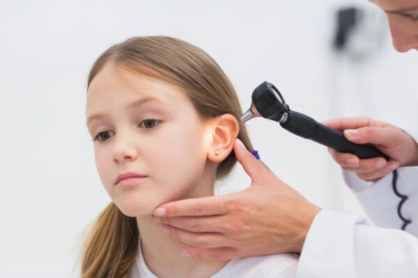 Doctor examining girl's ear with otoscope.