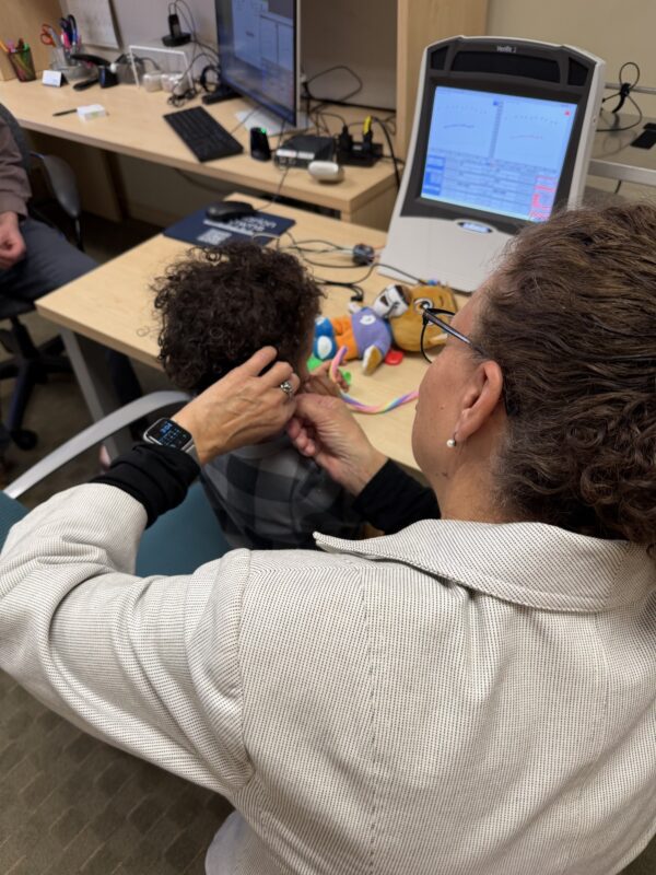 Child receiving hearing test in clinic.
