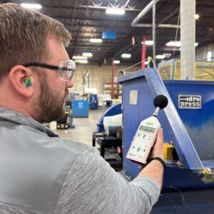 Man measuring noise levels in factory.